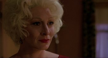 Movie still from “The Grifters” (1990), directed by Stephen Frears – An older woman with blonde curly hair wearing a red dress; Close Up shot, Over the shoulder angle