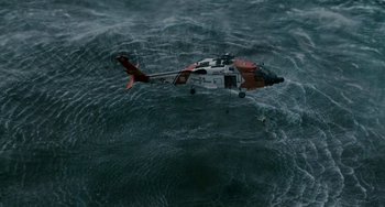 Movie still from “The Guardian” (2006), directed by Andrew Davis – A red and white helicopter flying over a body of water; Extreme Wide shot, Overhead angle