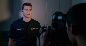 Movie still from “The Guardian” (2006), directed by Andrew Davis – A coast guard officer is being filmed in a mirror; Medium shot, Over the shoulder angle