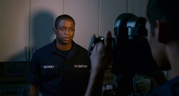 Movie still from “The Guardian” (2006), directed by Andrew Davis – A man in a uniform is taking a picture of another man in a uniform; Medium shot, Over the shoulder angle
