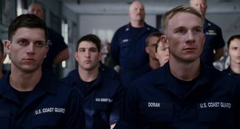 Movie still from “The Guardian” (2006), directed by Andrew Davis – A group of men in navy uniforms sitting next to each other; Medium shot, Over the shoulder angle