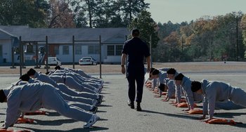 Movie still from “The Guardian” (2006), directed by Andrew Davis – A group of people doing push - ups in front of a police officer; Wide shot, Low angle