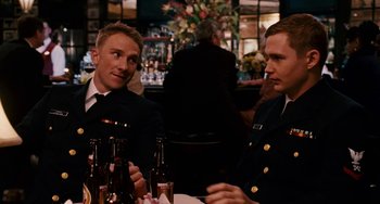 Movie still from “The Guardian” (2006), directed by Andrew Davis – A couple of men sitting next to each other at a table; Medium shot, Over the shoulder angle
