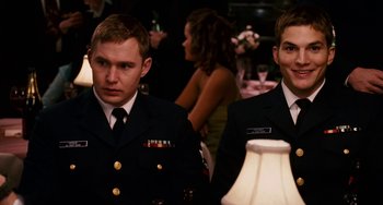 Movie still from “The Guardian” (2006), directed by Andrew Davis – A couple of men standing next to each other in a room; Medium shot, Over the shoulder angle