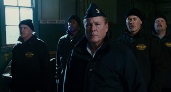 Movie still from “The Guardian” (2006), directed by Andrew Davis – A group of men standing next to each other in a room; Medium shot, Low angle