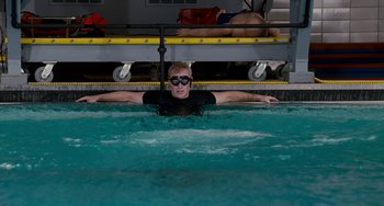 Movie still from “The Guardian” (2006), directed by Andrew Davis – A man swimming in a pool with a boat in the background; Wide shot, High angle