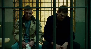 Movie still from “The Guardian” (2006), directed by Andrew Davis – Two men sitting next to each other in a jail cell; Medium shot, Low angle
