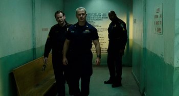 Movie still from “The Guardian” (2006), directed by Andrew Davis – A group of men standing next to each other in a room; Medium shot, Low angle