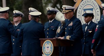 Movie still from “The Guardian” (2006), directed by Andrew Davis – A group of men standing next to each other on a stage; Medium shot, Over the shoulder angle