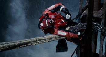 Movie still from “The Guardian” (2006), directed by Andrew Davis – A man in red and white jacket climbing a rope; Wide shot, Overhead angle