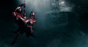 Movie still from “The Guardian” (2006), directed by Andrew Davis – A man in a red suit is hanging from a rope; Wide shot, Low angle