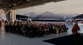 Movie still from “The Guardian” (2006), directed by Andrew Davis – A large group of people sitting in front of an airplane; Extreme Wide shot, High angle