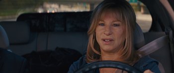 Movie still from “The Guilt Trip” (2012), directed by Anne Fletcher – A person sitting in a car with a steering wheel; Close Up shot, Over the shoulder angle