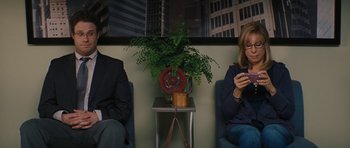 Movie still from “The Guilt Trip” (2012), directed by Anne Fletcher – Two people sitting in a waiting room next to a plant; Medium shot, High angle