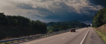 Movie still from “The Guilt Trip” (2012), directed by Anne Fletcher – A car driving down a road under a cloudy sky; Extreme Wide shot, High angle