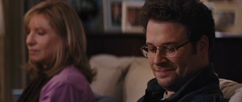 Movie still from “The Guilt Trip” (2012), directed by Anne Fletcher – A person sitting on a couch wearing glasses; Close Up shot, Over the shoulder angle