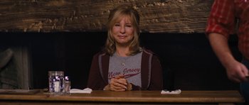 Movie still from “The Guilt Trip” (2012), directed by Anne Fletcher – A woman sitting at a table with her hands clasped together; Medium shot, Over the shoulder angle