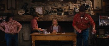 Movie still from “The Guilt Trip” (2012), directed by Anne Fletcher – A woman sitting at a wooden table in front of two men; Wide shot, Over the shoulder angle