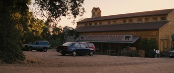 Movie still from “The Guilt Trip” (2012), directed by Anne Fletcher – A car is parked in front of an old building; Extreme Wide shot, Low angle