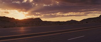 Movie still from “The Guilt Trip” (2012), directed by Anne Fletcher – The sun is setting over a mountain range and a highway; Extreme Wide shot, Low angle