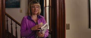Movie still from “The Guilt Trip” (2012), directed by Anne Fletcher – A woman in a purple jacket is holding a stack of papers; Medium shot, Over the shoulder angle