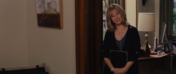 Movie still from “The Guilt Trip” (2012), directed by Anne Fletcher – A woman standing in a room holding a laptop; Medium shot, Over the shoulder angle