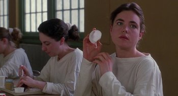 Movie still from “The Handmaid's Tale” (1990), directed by Volker Schlöndorff – Two women sitting at a table holding a white object; Close Up shot, Over the shoulder angle
