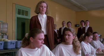 Movie still from “The Handmaid's Tale” (1990), directed by Volker Schlöndorff – A group of people in a room with a woman standing in front of them; Medium shot, Low angle