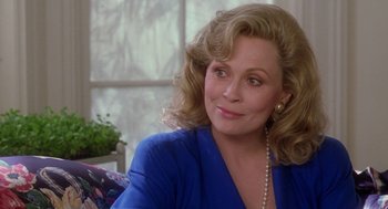 Movie still from “The Handmaid's Tale” (1990), directed by Volker Schlöndorff – An older woman wearing a blue shirt and pearl necklace; Close Up shot, Over the shoulder angle