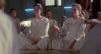 Movie still from “The Handmaid's Tale” (1990), directed by Volker Schlöndorff – A group of people sitting on the floor wearing white clothes; Medium shot, Over the shoulder angle