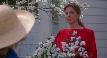 Movie still from “The Handmaid's Tale” (1990), directed by Volker Schlöndorff – A woman in a red shirt holding a bouquet of flowers; Close Up shot, Over the shoulder angle