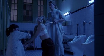 Movie still from “The Handmaid's Tale” (1990), directed by Volker Schlöndorff – A woman is being whipped in a bathroom by another woman; Medium shot, Low angle