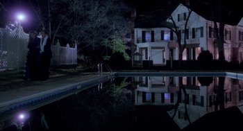 Movie still from “The Handmaid's Tale” (1990), directed by Volker Schlöndorff – Two people are standing by a pool at night; Extreme Wide shot, High angle