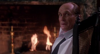 Movie still from “The Handmaid's Tale” (1990), directed by Volker Schlöndorff – A man standing in front of a fireplace; Close Up shot, Over the shoulder angle