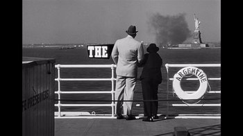 Movie still from “The Harder They Fall” (1956), directed by Mark Robson – A man and a woman standing on a pier looking out over the water; Wide shot, Over the shoulder angle