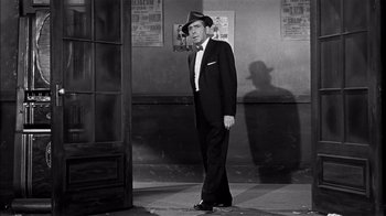 Movie still from “The Harder They Fall” (1956), directed by Mark Robson – A black and white photo of a man in a suit and hat; Medium shot, Low angle