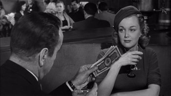 Movie still from “The Harder They Fall” (1956), directed by Mark Robson – An old photo of a man and a woman in a restaurant; Medium shot, Over the shoulder angle