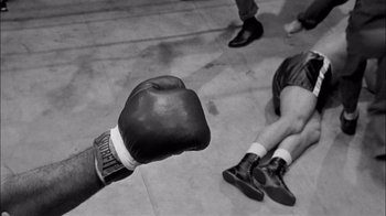 Movie still from “The Harder They Fall” (1956), directed by Mark Robson – A person wearing a boxing glove is holding his hand up to the ground; Extreme Close Up shot, Overhead angle