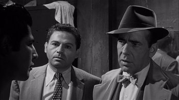 Movie still from “The Harder They Fall” (1956), directed by Mark Robson – A black - and - white photo of two men in suits and ties; Close Up shot, Over the shoulder angle