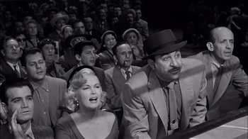 Movie still from “The Harder They Fall” (1956), directed by Mark Robson – A group of people sitting in front of each other; Medium shot, Low angle