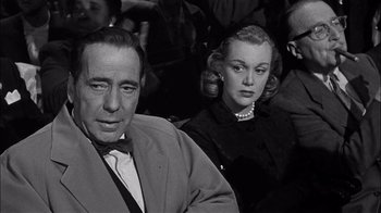 Movie still from “The Harder They Fall” (1956), directed by Mark Robson – A man and a woman sitting next to each other; Close Up shot, Over the shoulder angle