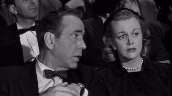 Movie still from “The Harder They Fall” (1956), directed by Mark Robson – An older man and a younger woman sitting next to each other; Close Up shot, Low angle