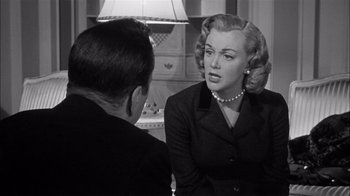 Movie still from “The Harder They Fall” (1956), directed by Mark Robson – An old photo of a man and a woman talking to each other; Medium shot, Over the shoulder angle