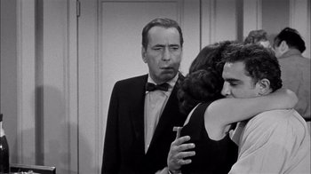 Movie still from “The Harder They Fall” (1956), directed by Mark Robson – A man in a suit and tie holding a cell phone; Medium shot, Over the shoulder angle