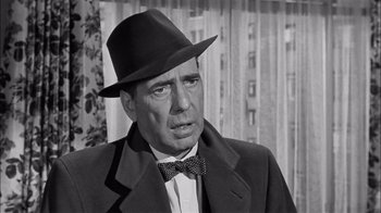 Movie still from “The Harder They Fall” (1956), directed by Mark Robson – An old photo of a man wearing a hat and a bow tie; Close Up shot, Over the shoulder angle