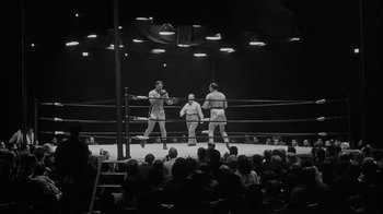 Movie still from “The Harder They Fall” (1956), directed by Mark Robson – Three men are boxing in a boxing ring; Wide shot, High angle