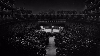 Movie still from “The Harder They Fall” (1956), directed by Mark Robson – A boxing match is being held in a large stadium; Extreme Wide shot, High angle