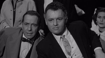 Movie still from “The Harder They Fall” (1956), directed by Mark Robson – A black and white photo of two men in suits and ties; Medium shot, Low angle