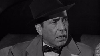 Movie still from “The Harder They Fall” (1956), directed by Mark Robson – A man wearing a hat and a bow tie; Close Up shot, Low angle