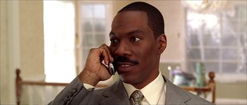 Movie still from “The Haunted Mansion” (2003), directed by Rob Minkoff – A man talking on a cell phone while wearing a suit and tie; Close Up shot, Low angle